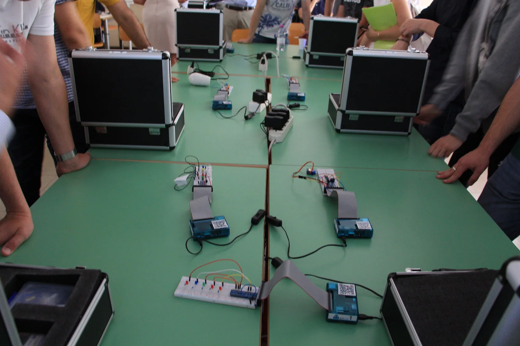 Banchi del laboratorio IoTLAB con valigette, prototipi elettronici e le mani degli studenti al lavoro